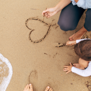Familie malt Herz in den Sand
