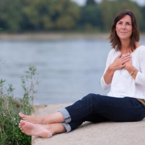 Frau sitzt auf einem Felsen mit den Händen auf dem Herzen